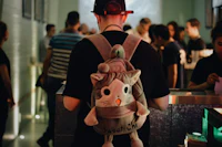 a man wearing a backpack with a stuffed cat on it