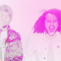 two men with curly hair standing in front of a pink background