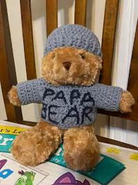 a crocheted teddy bear wearing a sweater and hat