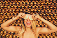 a woman holding a slice of lemon in front of a gold skull wall