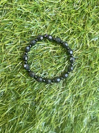 a black bead bracelet is laying on the grass