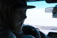 a man in a hoodie driving a car