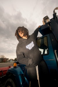 a woman with dreadlocks leaning on the back of a truck