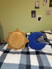 a crocheted sun and moon pillow on a bed