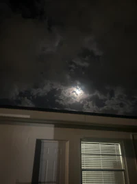 a full moon is seen through a window of a building