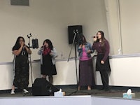 a group of women singing in front of a microphone