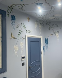 a room with a blue wall decorated with birds and flowers