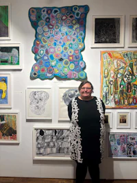 a woman standing in front of a wall full of paintings