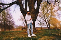 a man standing next to a tree with a cell phone