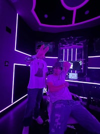 two men standing in a room with purple lights
