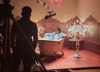 a man sitting in a bathtub in front of a chandelier