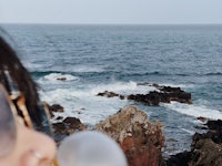 a woman is looking at the ocean with a bubble in her mouth