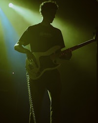 a man playing a bass guitar in a dark room