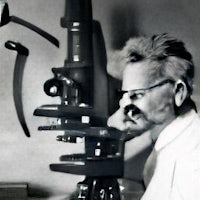 an old photo of a man looking through a microscope