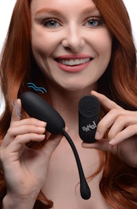 a woman with red hair holding a black vibrator