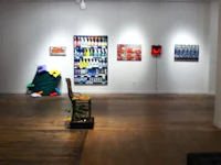 an art gallery with paintings and a chair