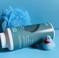 a blue rubber duck sits next to a bottle of shampoo