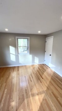an empty room with hardwood floors and a window