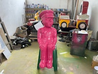 a pink statue of a man sitting on a chair
