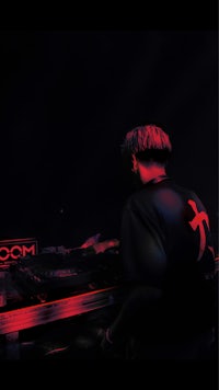 a man in a red shirt is djing in a dark room