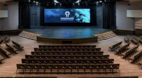a large auditorium with rows of chairs and a screen