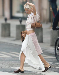 a woman in a white top and skirt crossing the street