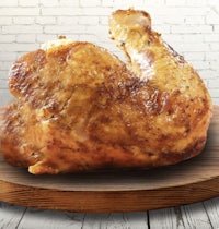 a roasted chicken sitting on a wooden board
