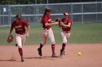 three softball players running on a field