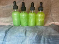 four bottles of green liquid sitting on a bed