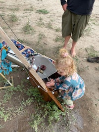 a little girl playing with a wooden box on the ground
