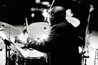 a black and white photo of a man playing drums