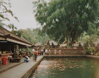 a group of people standing near a pond