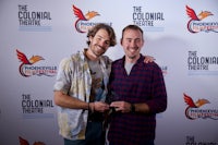 two men standing next to each other at the colonial theatre