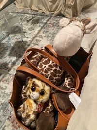 a stuffed giraffe in a brown bag on a bed