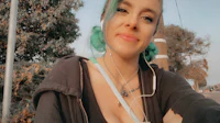 a woman with green hair and earphones taking a selfie