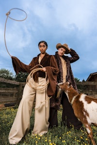 two women in cowboy hats and cowboy hats standing next to a goat