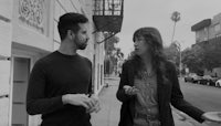 black and white photo of a man and woman talking on a sidewalk