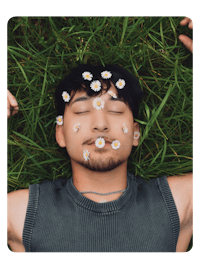 a man laying in the grass with daisies on his face
