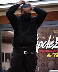 a man wearing a mask standing in front of a restaurant