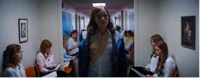 a woman is standing in a hallway with other women