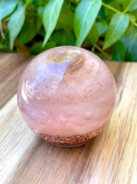 a pink quartz ball sitting on top of a wooden table
