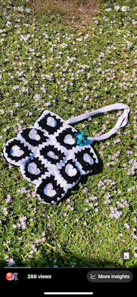 a black and white crocheted bag laying in the grass
