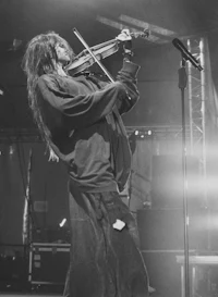 a man with long hair playing a violin on stage