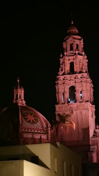 a pink tower lit up at night in front of a building