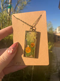 a person holding a necklace with a yellow flower on it