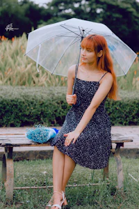 a woman sitting on a bench holding an umbrella