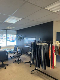 an office with a lot of clothes hanging on racks