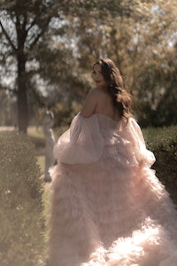 a woman in a pink dress is walking in a park