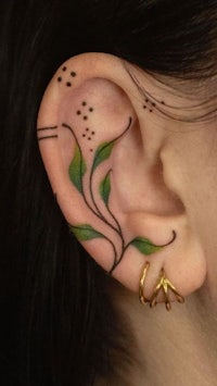 a woman's ear with a leaf tattoo
