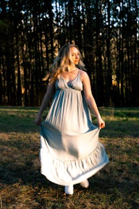 a woman in a long dress standing in a field